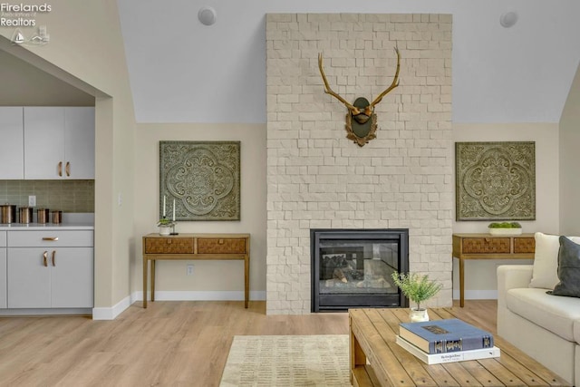 1861 N Opfer Lentz Rd, Martin, OH 43445 - living area featuring light wood-style flooring, vaulted ceiling, baseboards, and a brick fireplace
