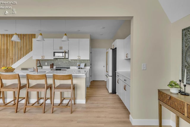 1861 N Opfer Lentz Rd, Martin, OH 43445 - kitchen with freestanding refrigerator, light wood-type flooring, a kitchen breakfast bar, light countertops, and tasteful backsplash