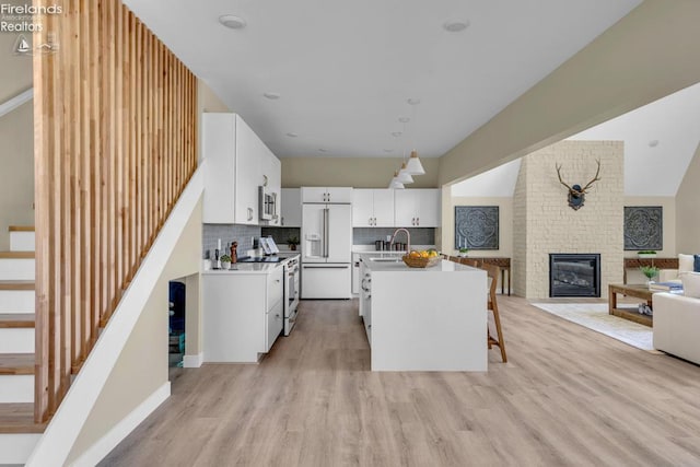 1861 N Opfer Lentz Rd, Martin, OH 43445 - kitchen featuring white appliances, a sink, light wood-style flooring, white cabinetry, and a brick fireplace