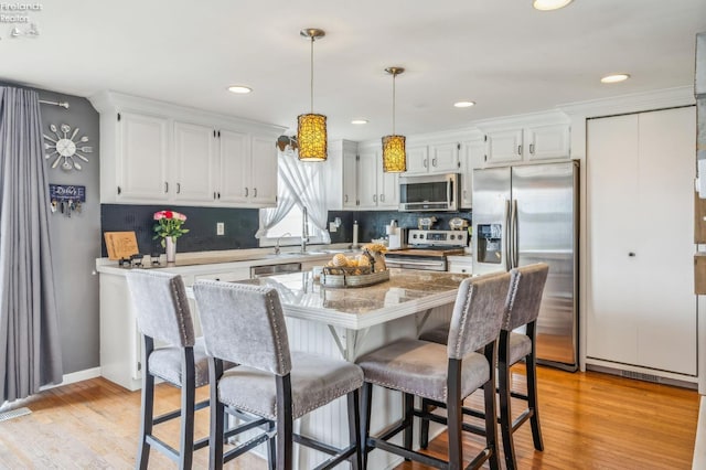 6518 W Township Road 112, Fostoria, OH 44830 - kitchen with appliances with stainless steel finishes, white cabinets, backsplash, decorative light fixtures, and light wood finished floors