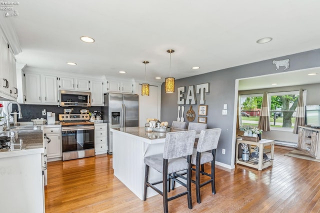 6518 W Township Road 112, Fostoria, OH 44830 - kitchen featuring stainless steel appliances, a sink, white cabinetry, light wood-style flooring, and a center island