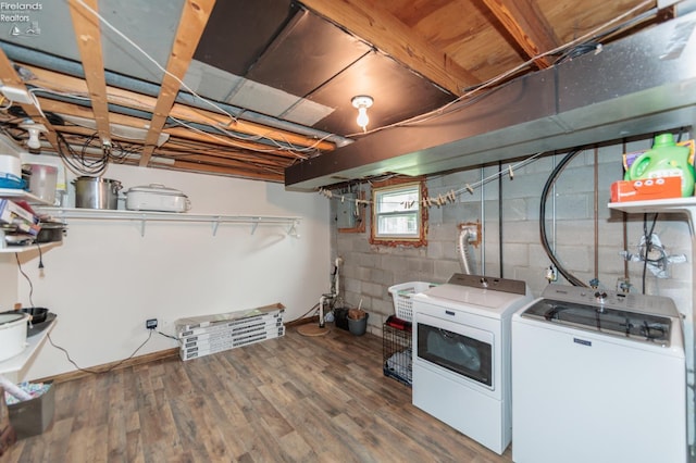 washroom with independent washer and dryer, wood finished floors, and concrete block wall