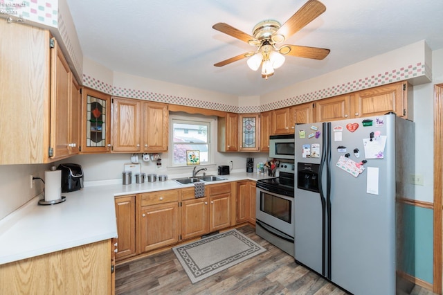 kitchen featuring appliances with stainless steel finishes, a sink, light countertops, light wood finished floors, and ceiling fan