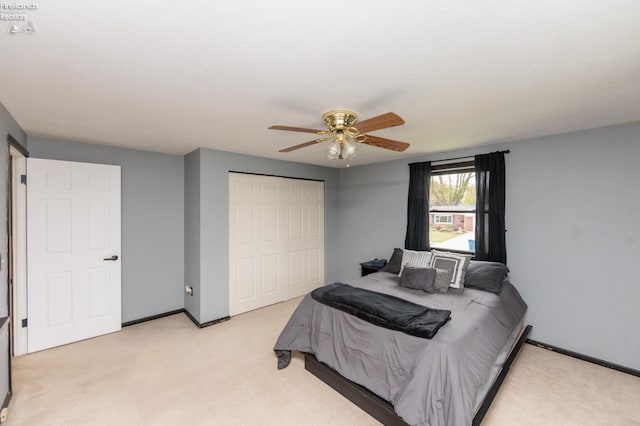 bedroom with light carpet, a closet, baseboards, and ceiling fan