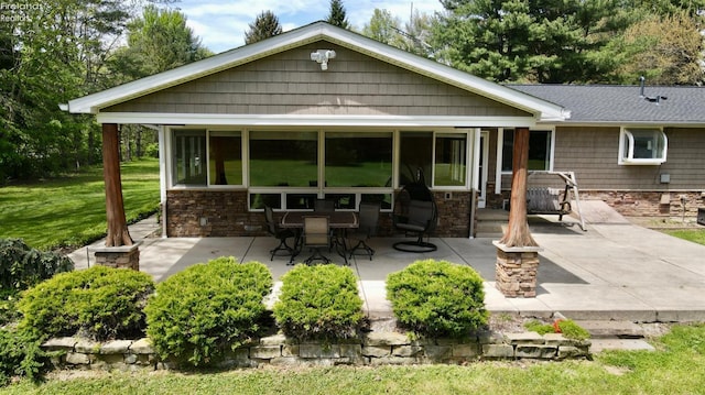 rear view of house with a patio area, an outdoor fire pit, and a sunroom
