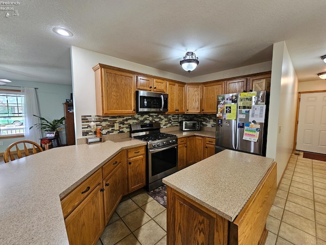 238 Nathan Dr, Clyde, OH 43410 - kitchen featuring appliances with stainless steel finishes, backsplash, light countertops, light tile patterned flooring, and a textured ceiling