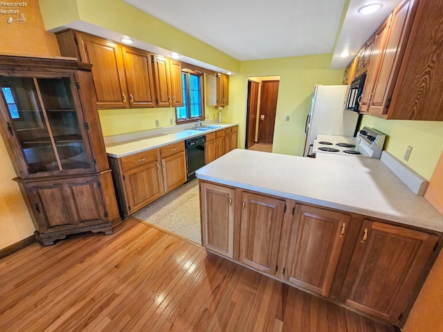110 Orchard Grove Dr, Clyde, OH 43410 - kitchen featuring black appliances, a sink, light wood-style flooring, a peninsula, and light countertops
