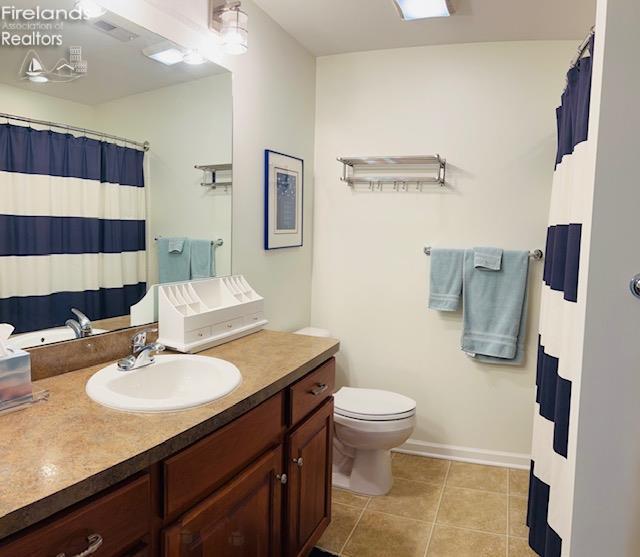 2780 Canterbury Ln Unit A, Port Clinton, OH 43452 - full bath featuring tile patterned floors, toilet, vanity, baseboards, and curtained shower
