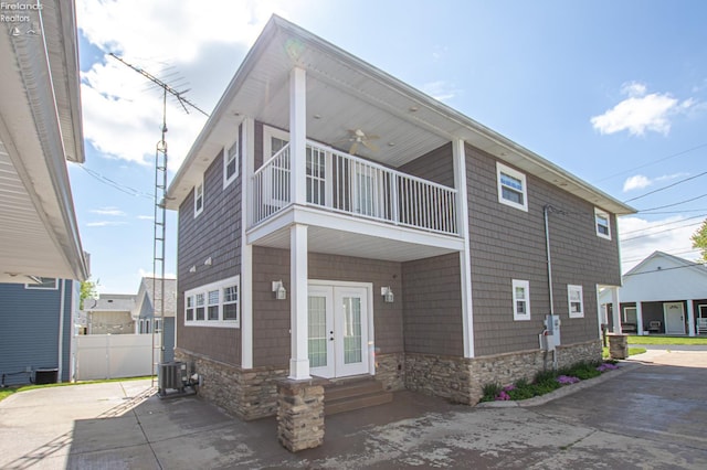 5475 E Mabel Dr, Port Clinton, OH 43452 - back of house featuring french doors, a balcony, stone siding, central AC, and concrete driveway