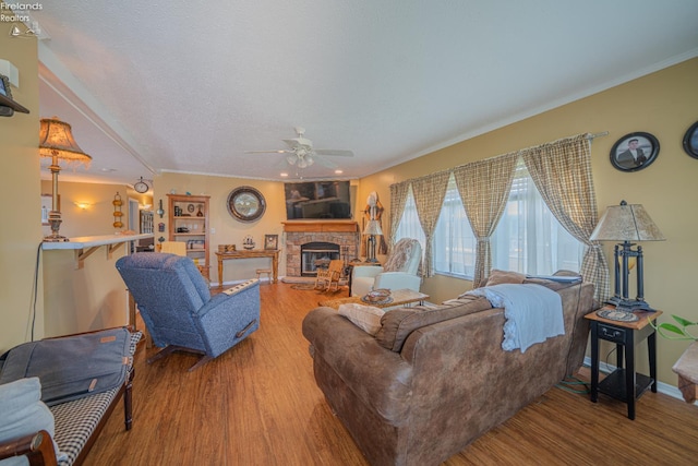 8896 White Crane Way, Oak Harbor, OH 43449 - living area featuring wood finished floors, a stone fireplace, a ceiling fan, crown molding, and baseboards