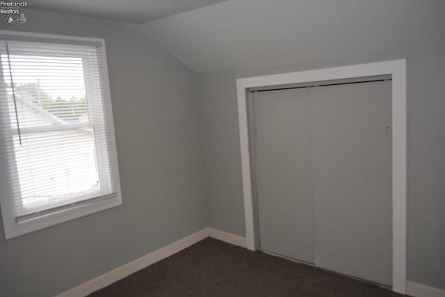 26 Marshall St, Norwalk, OH 44857 - unfurnished bedroom with vaulted ceiling, multiple windows, a closet, baseboards, and dark colored carpet