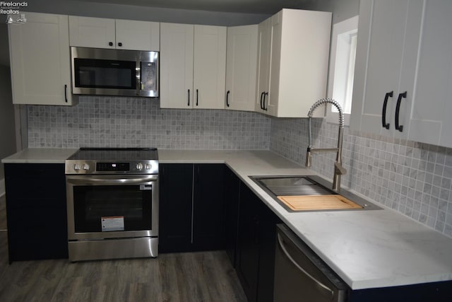 26 Marshall St, Norwalk, OH 44857 - kitchen with stainless steel appliances, a sink, wood finished floors, white cabinets, and tasteful backsplash