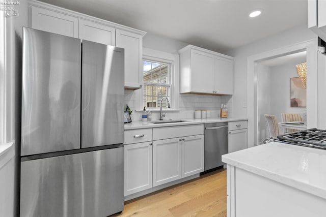 625 Laurel Ave, Port Clinton, OH 43452 - kitchen with stainless steel appliances, a sink, decorative backsplash, white cabinetry, and light wood finished floors