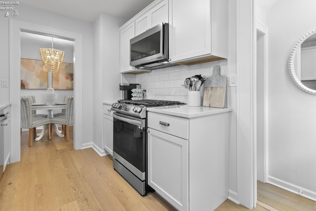 625 Laurel Ave, Port Clinton, OH 43452 - kitchen featuring stainless steel appliances, light wood-style flooring, light countertops, a chandelier, and white cabinets