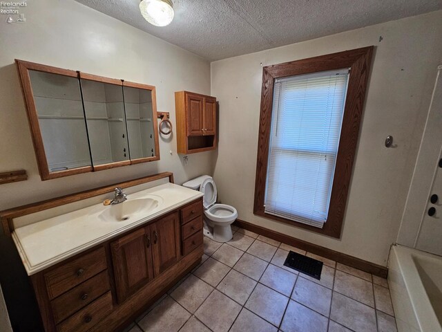 202 Duane St, Clyde, OH 43410 - bathroom featuring a textured ceiling, vanity, toilet, baseboards, and a tub to relax in
