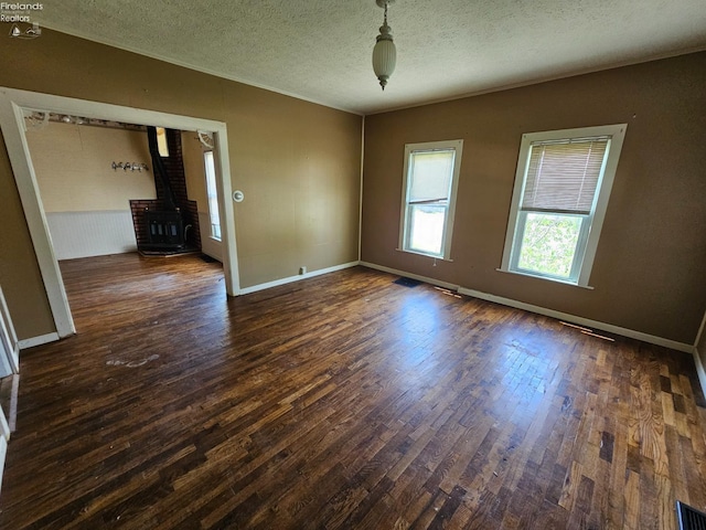 202 Duane St, Clyde, OH 43410 - empty room with a wood stove, wood finished floors, a textured ceiling, and baseboards