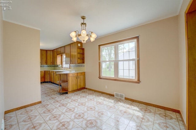 419 Kinney St, Bellevue, OH 44811 - kitchen featuring open shelves, light countertops, brown cabinetry, a chandelier, and baseboards