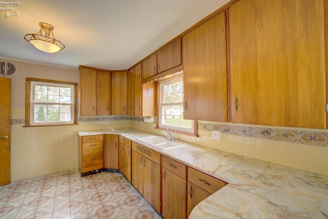 419 Kinney St, Bellevue, OH 44811 - kitchen with a sink, light countertops, plenty of natural light, brown cabinetry, and tile walls