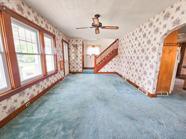 124 Walter St, Bellevue, OH 44811 - unfurnished living room featuring wallpapered walls, arched walkways, a textured ceiling, carpet flooring, and a ceiling fan