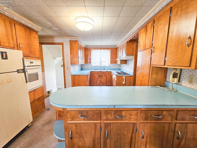 124 Walter St, Bellevue, OH 44811 - kitchen with white appliances, brown cabinetry, a peninsula, and wallpapered walls