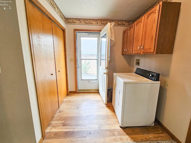 124 Walter St, Bellevue, OH 44811 - clothes washing area featuring washer / clothes dryer, light wood-style flooring, cabinet space, baseboards, and a textured ceiling
