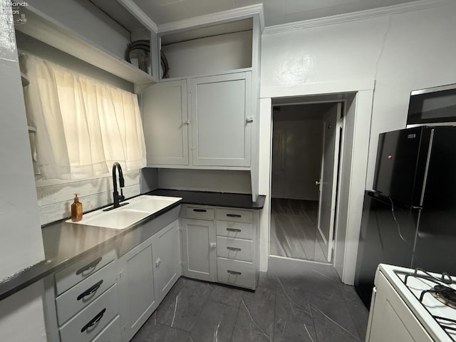 118 E 5th St, Port Clinton, OH 43452 - kitchen with a sink, range, freestanding refrigerator, dark countertops, and white cabinetry