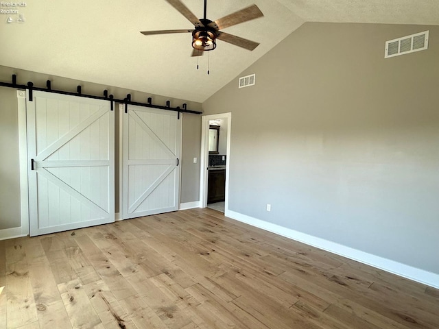 10556 E Bayshore Rd Unit 4C, Marblehead, OH 43440 - unfurnished bedroom featuring a barn door, baseboards, wood finished floors, and high vaulted ceiling