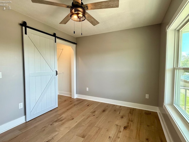 10556 E Bayshore Rd Unit 4C, Marblehead, OH 43440 - unfurnished bedroom featuring light wood-type flooring, baseboards, a barn door, and ceiling fan