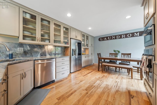 3999 NE Catawba Rd Unit 29, Port Clinton, OH 43452 - kitchen with stainless steel appliances, a sink, light wood-style flooring, backsplash, and dark stone countertops