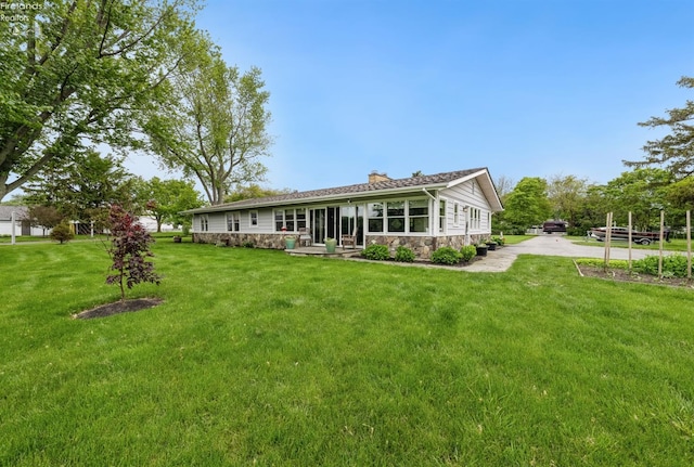 3999 NE Catawba Rd Unit 29, Port Clinton, OH 43452 - back of house with stone siding, a chimney, a lawn, and driveway