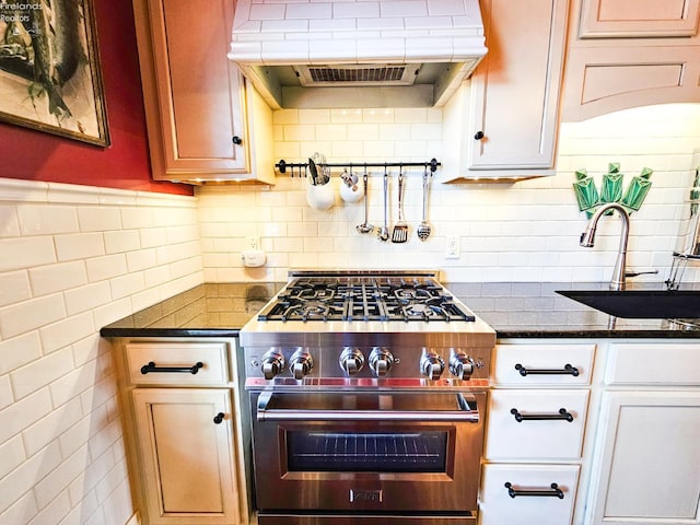133 E Forest St, Clyde, OH 43410 - kitchen with high end stainless steel range oven, exhaust hood, a sink, tile walls, and dark stone counters