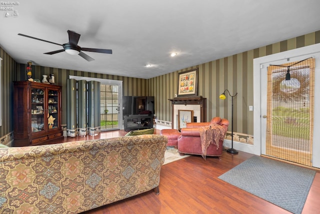 133 E Forest St, Clyde, OH 43410 - living room featuring wallpapered walls, ceiling fan, wood finished floors, a wood stove, and baseboards