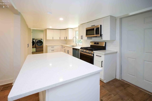 612 2nd St, Fremont, OH 43420 - kitchen with appliances with stainless steel finishes, washing machine and clothes dryer, a sink, a kitchen island, and decorative backsplash