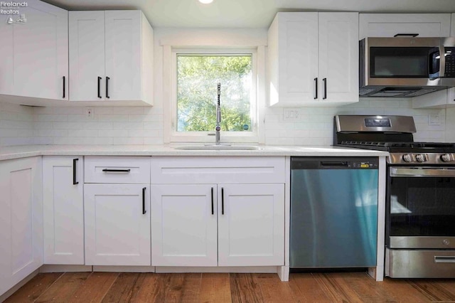 612 2nd St, Fremont, OH 43420 - kitchen featuring appliances with stainless steel finishes, white cabinetry, tasteful backsplash, and wood finished floors