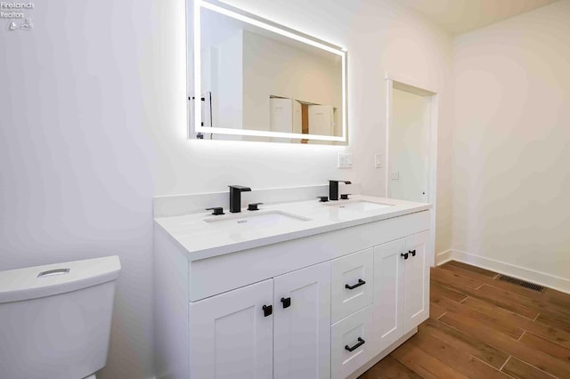 612 2nd St, Fremont, OH 43420 - bathroom featuring double vanity, toilet, wood finished floors, and baseboards
