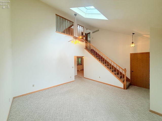 9343 E Bayshore Rd, Marblehead, OH 43440 - unfurnished living room with a skylight, stairway, carpet flooring, baseboards, and high vaulted ceiling