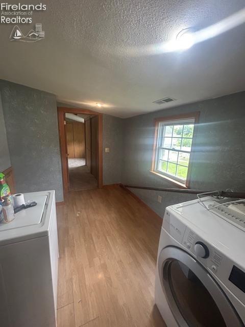 201 Heter St, Bellevue, OH 44811 - washroom with separate washer and dryer, light wood-type flooring, and a textured ceiling