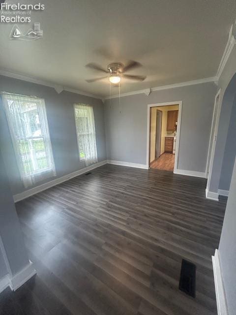 201 Heter St, Bellevue, OH 44811 - empty room with ornamental molding, a ceiling fan, baseboards, dark wood-type flooring, and arched walkways