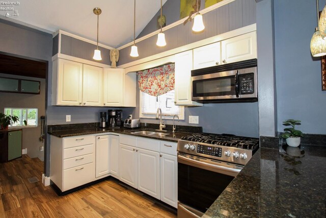 134 Hobson St, Bellevue, OH 44811 - kitchen with appliances with stainless steel finishes, a sink, vaulted ceiling, white cabinets, and wood finished floors