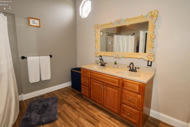 134 Hobson St, Bellevue, OH 44811 - bathroom with double vanity, wood finished floors, baseboards, and curtained shower