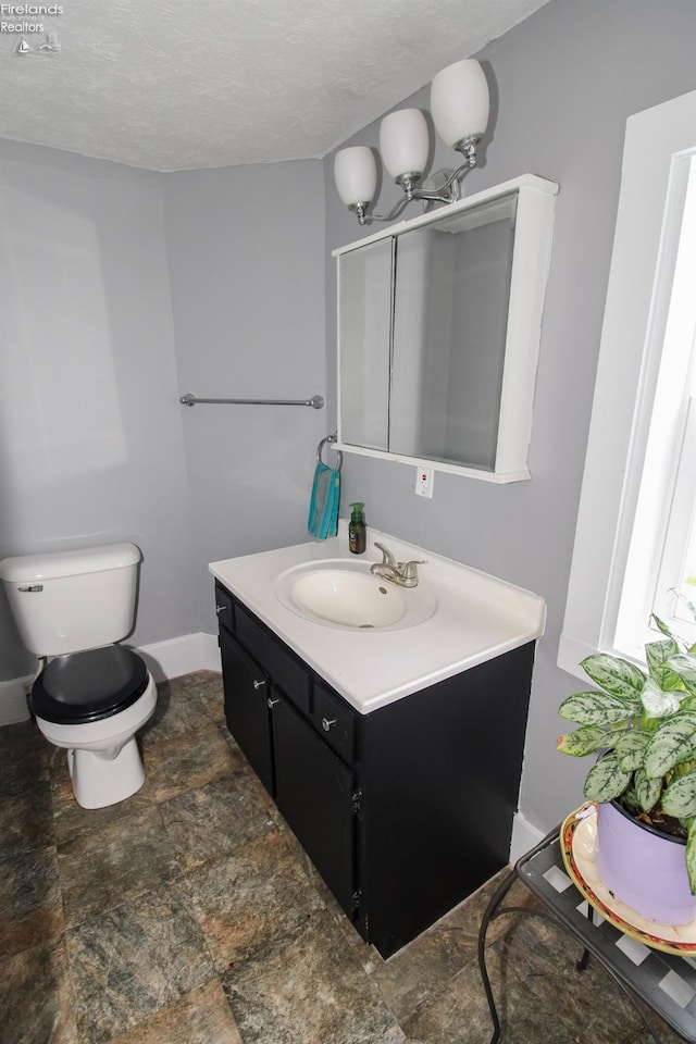 134 Hobson St, Bellevue, OH 44811 - half bath with vanity, toilet, stone finish floors, baseboards, and a textured ceiling