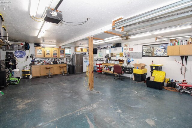 134 Hobson St, Bellevue, OH 44811 - garage featuring a workshop area, a garage door opener, and freestanding refrigerator