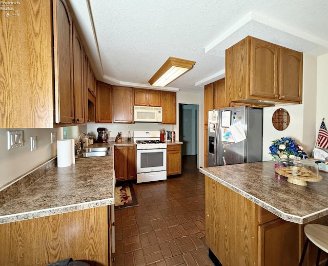 31 Mohawk St, Tiffin, OH 44883 - kitchen with white appliances, a sink, brown cabinets, a textured ceiling, and brick patterned floors