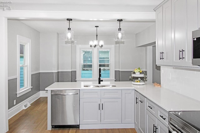 713 Madison St, Port Clinton, OH 43452 - kitchen with stainless steel appliances, a sink, light countertops, light wood-style floors, and hanging light fixtures