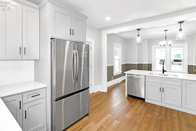 713 Madison St, Port Clinton, OH 43452 - kitchen featuring appliances with stainless steel finishes, a sink, light countertops, light wood-type flooring, and a chandelier