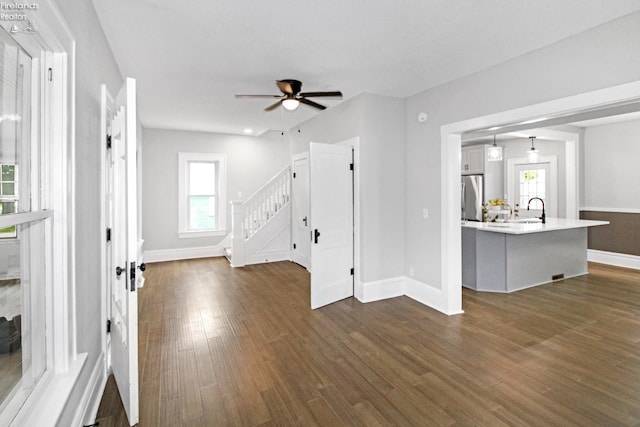 713 Madison St, Port Clinton, OH 43452 - unfurnished living room featuring a sink, stairway, dark wood finished floors, ceiling fan, and baseboards