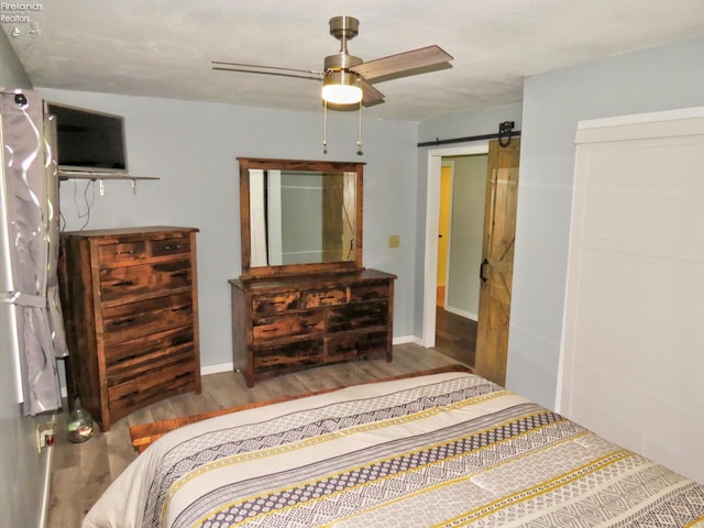 1319 Burkholder, Clyde, OH 43410 - bedroom featuring a barn door, wood finished floors, a ceiling fan, and baseboards