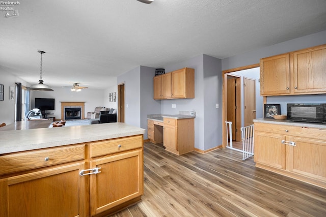 4936 Gibbs Rd, Norwalk, OH 44857 - kitchen with a fireplace, a ceiling fan, light wood finished floors, light countertops, and open floor plan