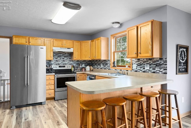 4936 Gibbs Rd, Norwalk, OH 44857 - kitchen with appliances with stainless steel finishes, under cabinet range hood, a sink, light wood finished floors, and a peninsula