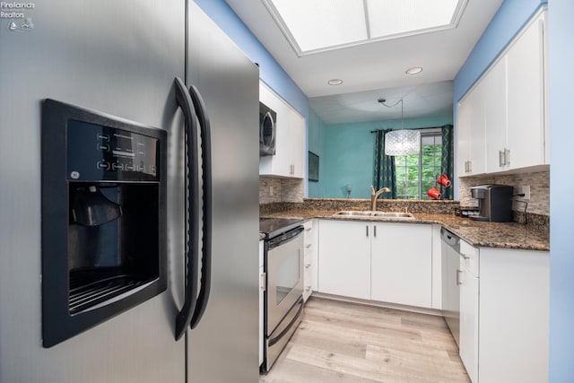 4370 Marin Woods Dr Unit D, Port Clinton, OH 43452 - kitchen with stainless steel appliances, a sink, light wood-type flooring, tasteful backsplash, and white cabinetry